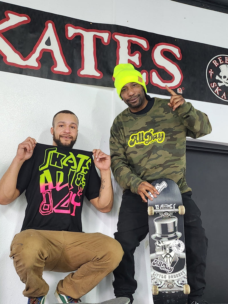 Two skateboarding men with All Day merch holding skateboards