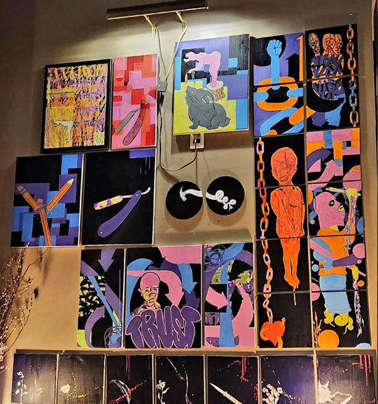 Colorful abstract paintings displayed on a wall in a galleria.