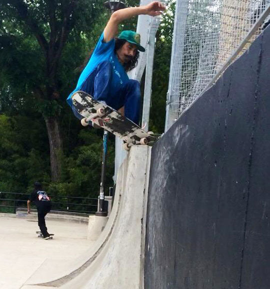 Skateboarder performing a trick on a ramp at a skate park.